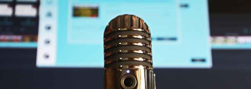 Shiny silver microphone in front of a blurry monitor.